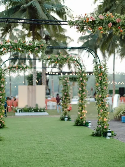 A beautiful garden reception entrance. A series of simple black arches adorned with florals creates an enchanting walkway for guests into the main celebration area.