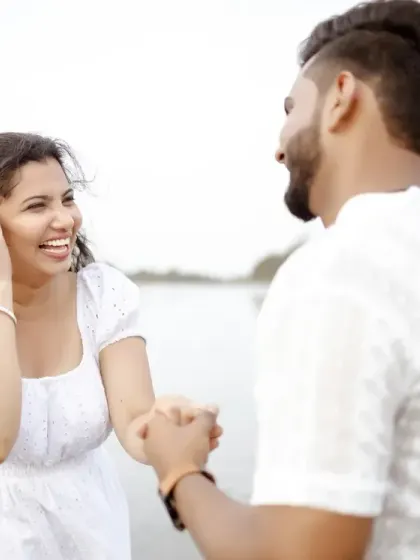 A sweet, candid interaction on the beach. The all-white outfits create a fresh and timeless look against the natural backdrop of the sea.