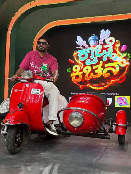 On the set of the 'Kwatle Kitchen' grand launch for Colors Kannada, posing with a classic scooter and sidecar prop. Props are a great way to make an entry memorable.