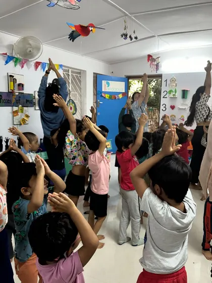 Children reach for the sky during a yoga pose. These moments of collective movement build a sense of community and shared experience.