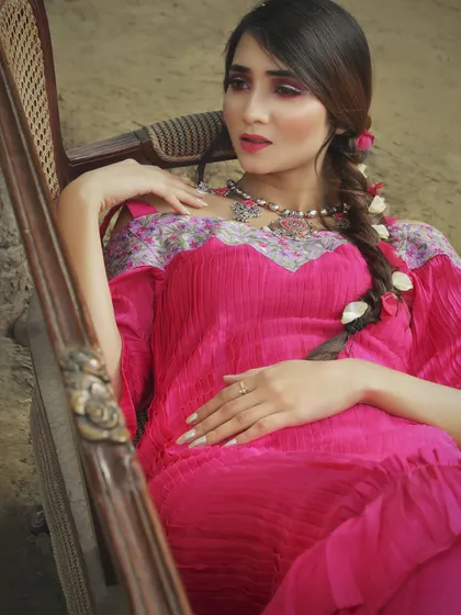 A detailed shot of a fuchsia pink pleated maxi dress I designed. The off-shoulder embroidered neckline adds a touch of Indian heritage to a modern, indie-chic silhouette perfect for a cocktail event.