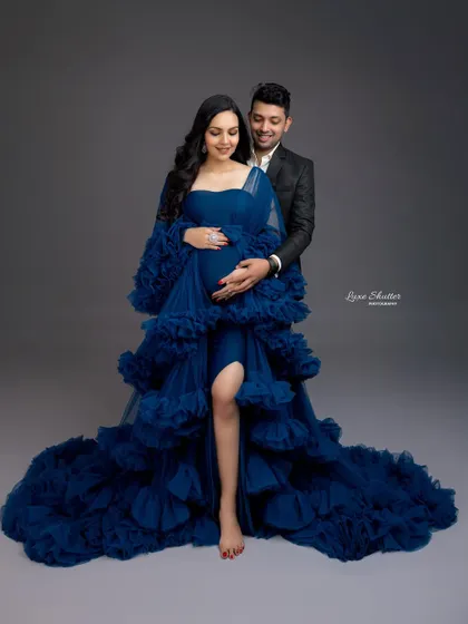 A beautiful couple's portrait featuring a dramatic blue ruffled gown. The way the partner embraces her shows the love and support surrounding this journey.