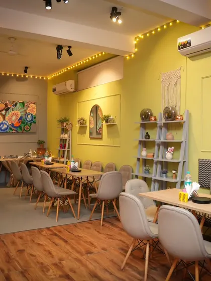 I welcome you all to a cozy space where you can make memories together. This is our cafe area, set up for a private event with warm lighting and comfortable seating.