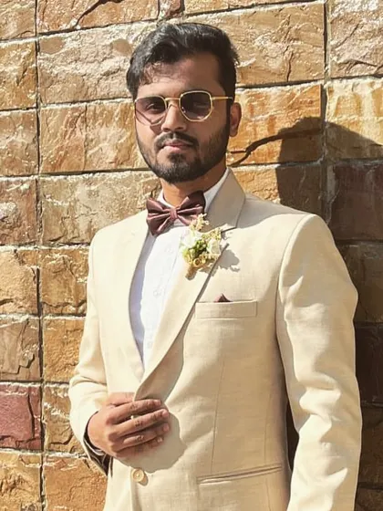 The groom's party deserves to look sharp too. Here is a closer look at a custom boutonniere, or spray, with a cream-colored flower and subtle greenery, designed to complement the groomsman's beige suit and bow tie for a Bombay Catholic wedding.