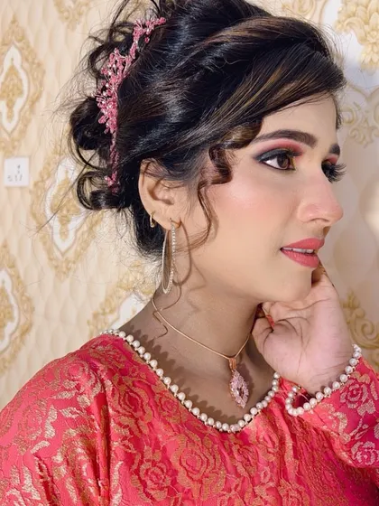 A side profile of the client in the pink dress, showing her glowing skin and colourful eye makeup.