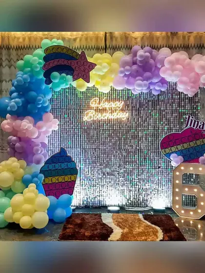 A colorful Pop-It themed decoration with a sequin backdrop, rainbow balloons, and a "6" marquee number.