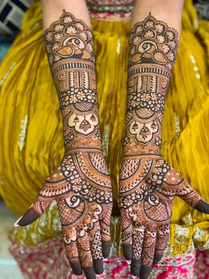 This design is filled with graceful peacock motifs, from the wristbands to the fingertips. The symmetry and flow of the patterns create a harmonious and elegant look for the bride.