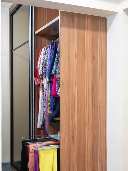 A sliding wardrobe with a mirrored panel and a wood-finish panel. The pull-out trouser rack is a smart feature for keeping clothes organized and wrinkle-free.