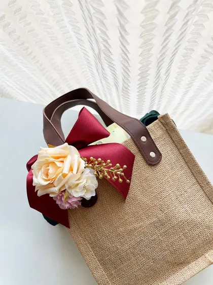 A close-up of the floral and ribbon detail on our jute welcome bag. We customize these embellishments to match your wedding colors and theme perfectly.