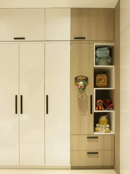 This wardrobe design combines white and wood-grain laminates for a timeless look. The open-shelf niche breaks up the solid-door facade and provides space for toys and decor.