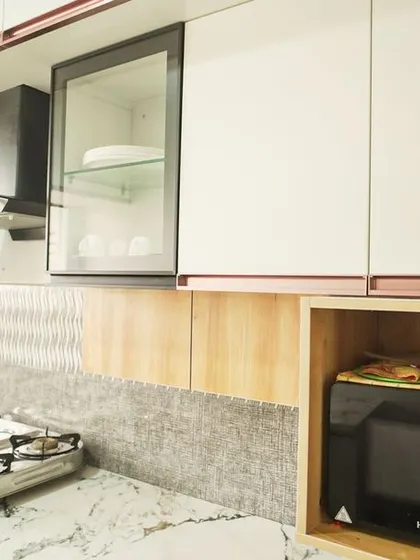 This shot highlights the open niche for a microwave, seamlessly integrated into the upper cabinetry. The textured backsplash continues behind it, ensuring a cohesive design.