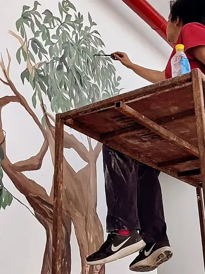 A candid shot of me on scaffolding, working on a large tree mural. This is a typical day in my life as a muralist.