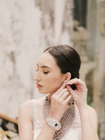 A delicate profile shot of a model adjusting her earring during a jewelry photoshoot. This candid-style photo beautifully captures the elegance of the diamond jewelry.