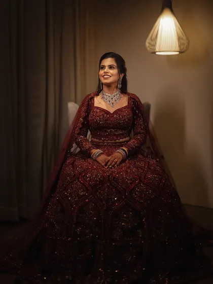A classic portrait of the bride in her magnificent red reception lehenga. Her happy, upward glance shows the joy and excitement of the evening.