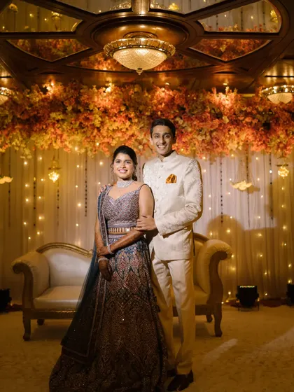 A grand reception stage for a beautiful couple. Her intricate lehenga is paired with a clean makeup look and a simple ponytail, letting her natural beauty and outfit shine.