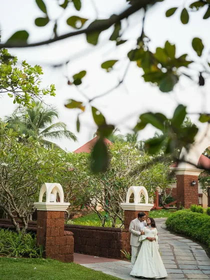 A romantic shot of the couple framed by the lush greenery and architecture of the Goa resort.
