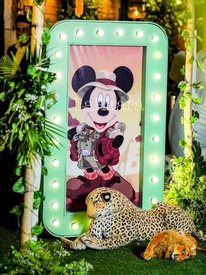 An illuminated frame showcasing safari Mickey, surrounded by greenery and a leopard prop. These light-up elements add a touch of glamour to the rustic jungle theme.
