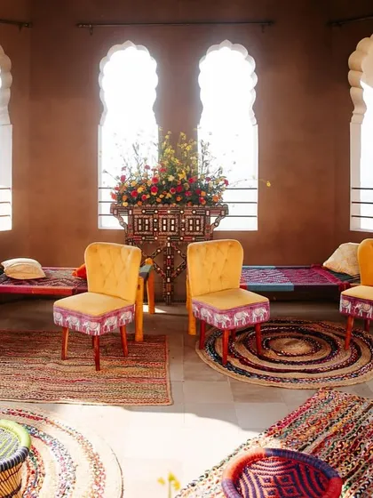 An intimate seating arrangement featuring custom-upholstered chairs and woven stools. Every piece of furniture was chosen to complement the vibrant, handcrafted feel of the Mela theme.