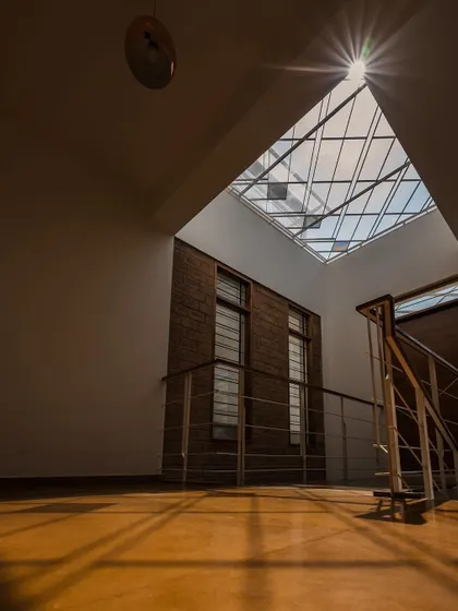 Sunlight bursts through a large skylight, casting strong shadows and illuminating the warm tones of the floor. We design these moments to create a powerful connection with the time of day and the weather outside.