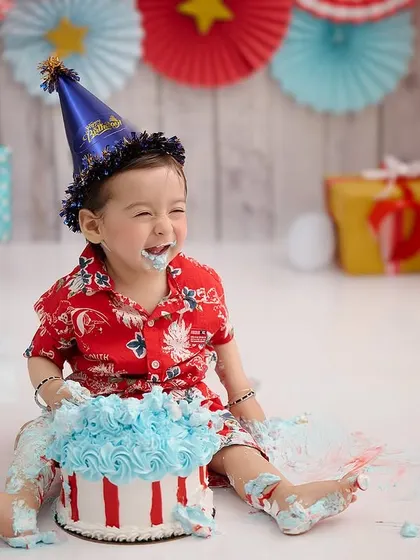 The pure joy of a birthday boy with his cake. The colorful party decor and his happy, frosting-covered face say it all.