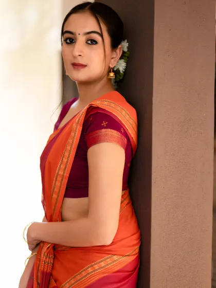 A classic, elegant pose against a simple wall. The focus is on the beautiful drape of the saree and the subject's graceful expression.