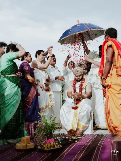 A candid moment of family showering the groom with flower petals during the 'kashi yatra' ritual.