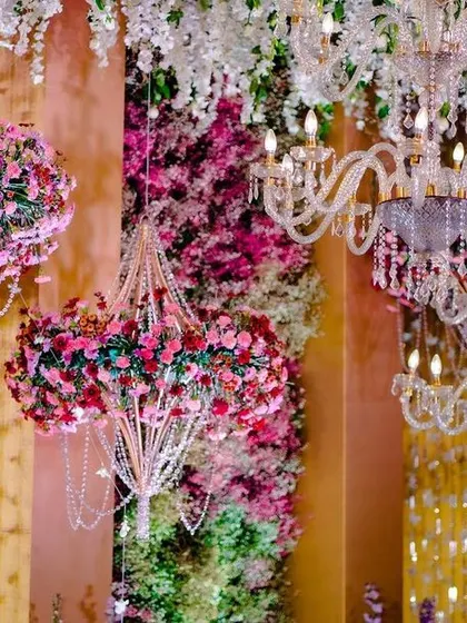 Detail of the hanging floral chandeliers from the 'Starry Night' reception. These custom pieces combine classic crystal chandeliers with lush pink floral arrangements for a unique and opulent look.