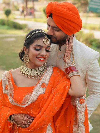 An intimate and affectionate portrait of the couple. The groom's gentle kiss on her forehead and her happy smile make this a truly heartwarming photo.