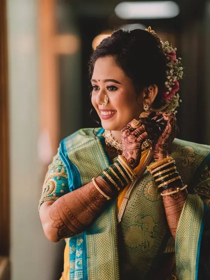 A candid moment of the bride getting ready. The soft, natural light from the window highlights the beautiful texture of her skin and the details of her makeup.