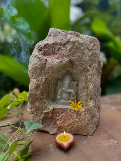 A small Ganesha figure carved into a natural rock niche, lit by a diya. This one-of-a-kind stone decor piece brings a charming, spiritual touch to your home for Diwali and beyond.