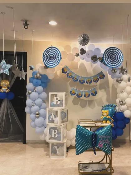 A full room decoration to welcome a baby boy. This setup includes a circular balloon arch, "BABY" blocks, and other themed elements in a cohesive blue and white color scheme.