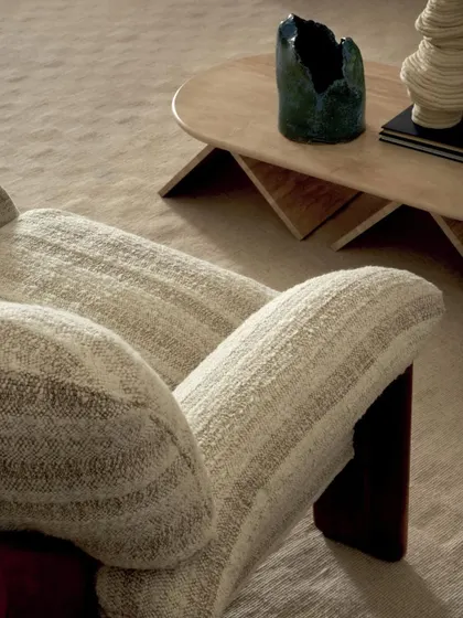 A detailed close-up of an armchair's upholstery, showcasing the flowing, undulating weave of the fabric. This shot emphasizes the tactile quality and subtle beauty of the high-end textiles we use for our bespoke furniture.