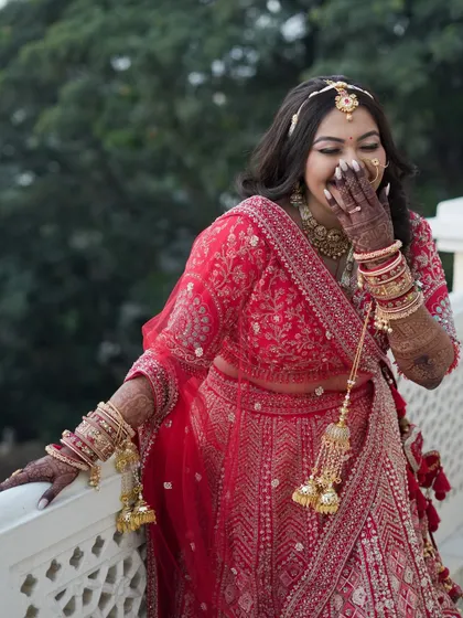 A candid moment of pure joy. This bride's classic red lehenga look is pure royalty, and her happy laugh shows that feeling beautiful on your wedding day is what truly matters.
