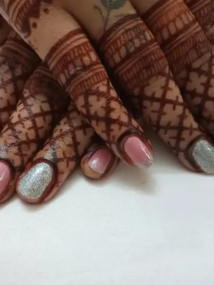 A simple and subtle gel nail paint on natural nails, paired with bridal henna. This look is perfect for clients who want an elegant and clean finish.
