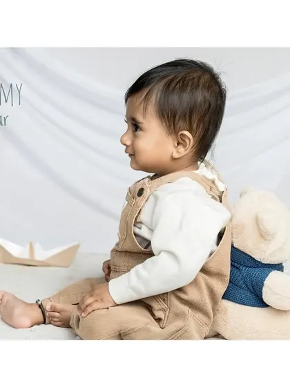 "Me and my teddy bear." A baby in cute dungarees sits with his bear, creating a nostalgic and heartwarming scene.