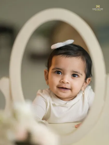 A beautiful baby girl looking at her reflection. We use simple props like this mirror to create sweet and introspective portraits.