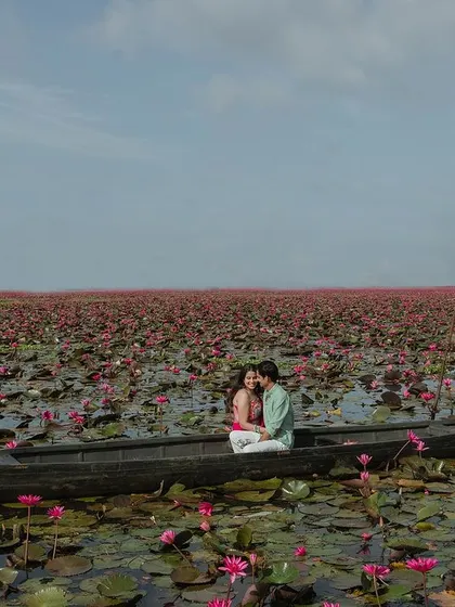 A wide shot showing the vastness of the lotus lake in Kerala. This image captures the scale of the beautiful landscape, with the couple enjoying a peaceful boat ride together.