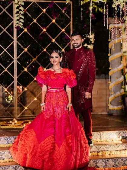 A vibrant and modern sangeet look. The bride's bright red and orange lehenga is paired with a fresh, glowing makeup look, perfect for a night of dancing.