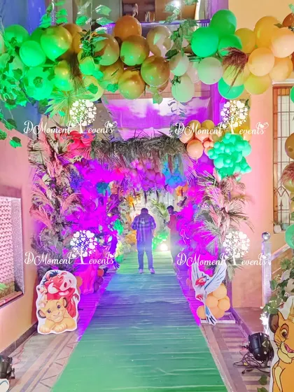 A magical jungle tunnel entrance, created with balloon arches, foliage, and colorful lighting to transport guests to Hakuna Matata.