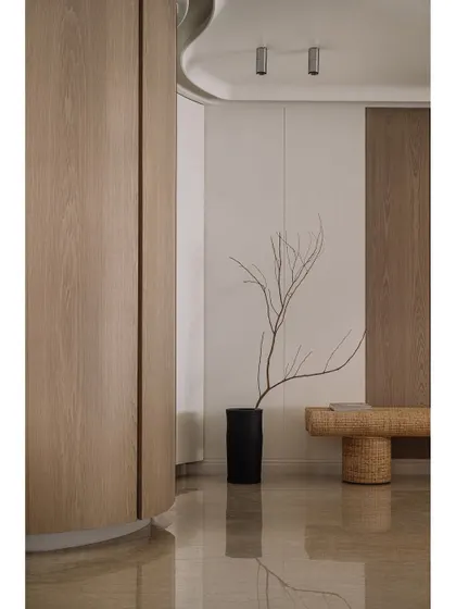 The entrance corridor of Kanso House, where curved wooden walls and a woven bench create a welcoming and organic first impression.