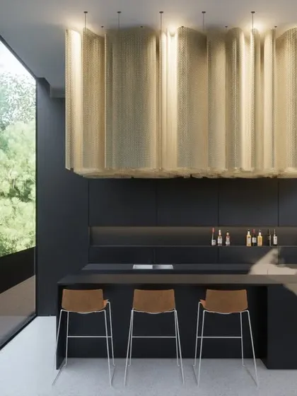 The bar area in the Hyderabad residence, featuring a dramatic metallic light fixture over a sleek, dark counter. Even in more intimate spaces, large windows ensure a constant connection to the lush greenery outside.