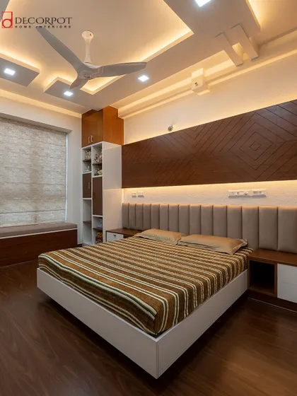This bedroom showcases a beautiful integration of a wardrobe, study nook, and a cozy bay window seating area. The warm wood tones and soft lighting create a perfect multi-functional retreat.