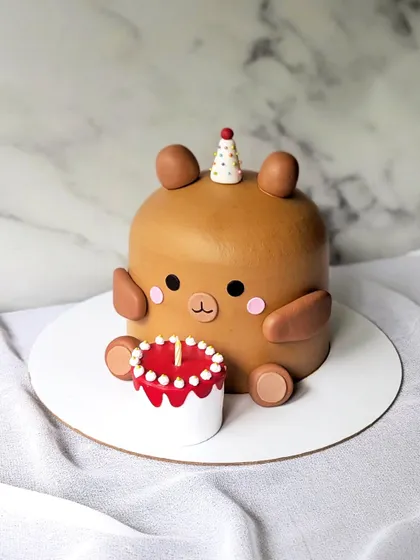 Don't you just want to cuddle this cutie? This adorable teddy bear-shaped cake is holding his own mini birthday cake.