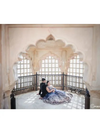 A quiet moment inside a palace, using the intricate arches and natural light from the jharokha windows to frame the couple. This shot highlights the stunning architecture while keeping the focus on their connection.