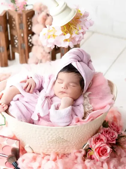 A fun and creative newborn spa day photoshoot, complete with a tiny pink bathrobe and a fluffy setting. These themed sessions are a unique way to announce your baby's arrival.