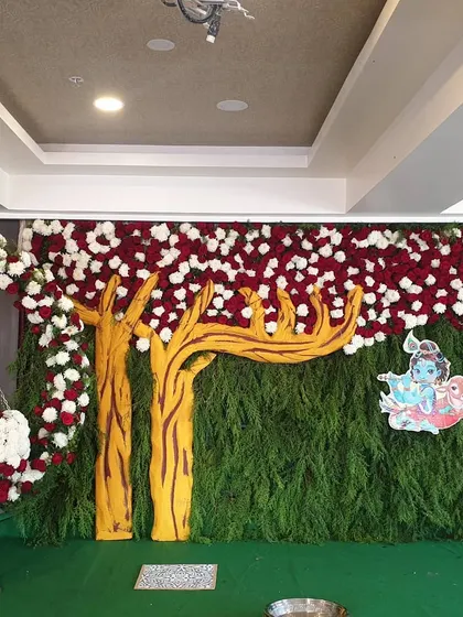 This is a full view of a Krishna-themed naming ceremony. I created a dense backdrop of foliage to represent a forest, complete with a custom tree cutout, a floral arch for the cradle, and a prominent illustration of Krishna to bring the theme to life.