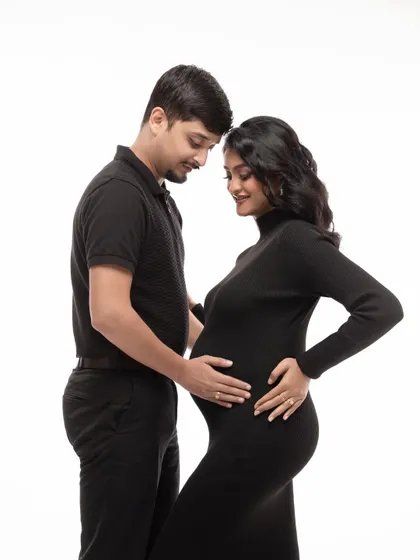 Including your partner is a wonderful way to capture the love and anticipation you share. This classic portrait, with simple black outfits against a clean white backdrop, focuses purely on the connection and tenderness between the expecting parents.
