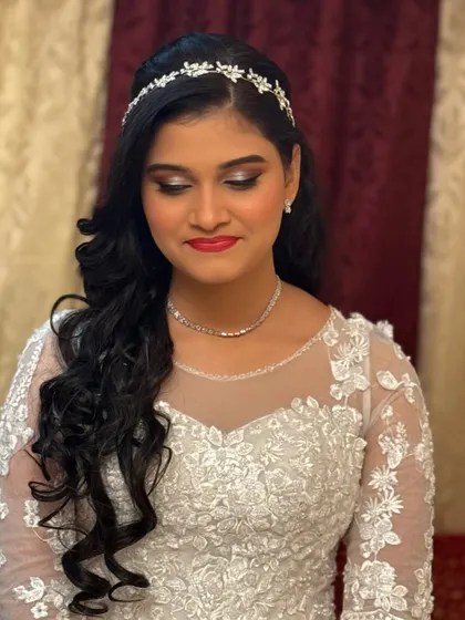 A radiant Christian bride ready for her forever. The makeup is classic and elegant, with a bold red lip and defined eyes to complement her beautiful white gown.