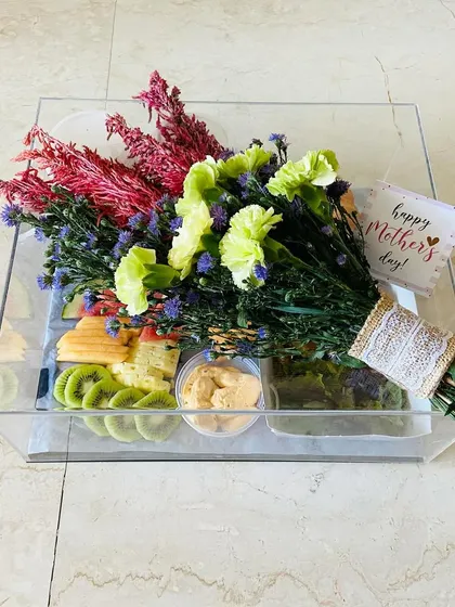 A Mother's Day pamper hamper designed for breakfast in bed. This acrylic tray holds a fresh floral bouquet alongside fruits, dip, and pastries for the perfect morning treat.
