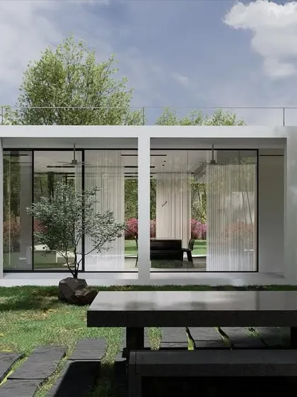This view shows the seamless connection between the indoor and outdoor spaces of the weekend retreat. The floor-to-ceiling glass walls of the minimalist structure can be opened completely, turning the living area into a covered veranda that merges with the lawn and garden.